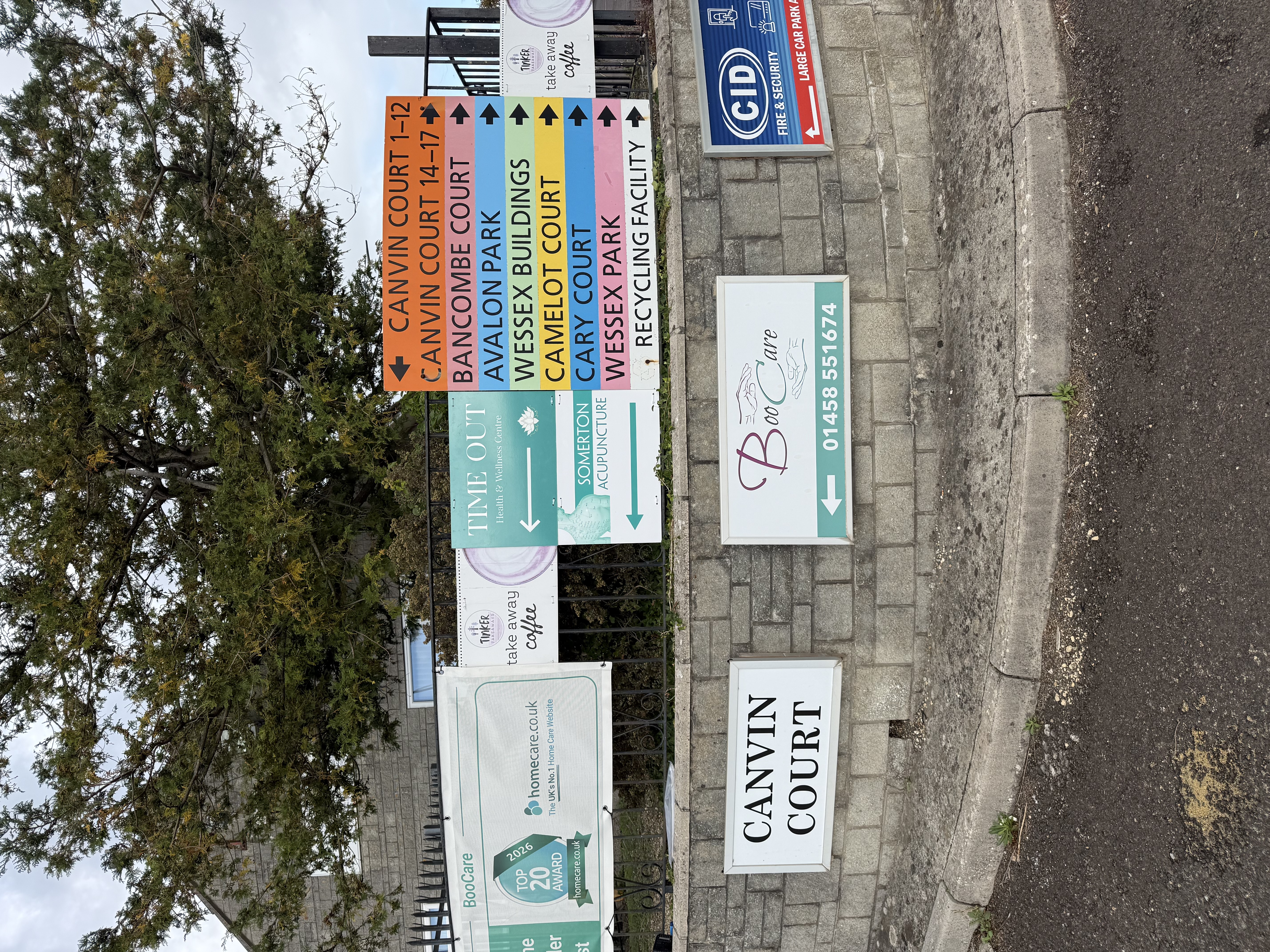 Railings at Canvin Court with a turquoise Time Out Health and Wellness Centre sign pointing left, beside the estate directory.